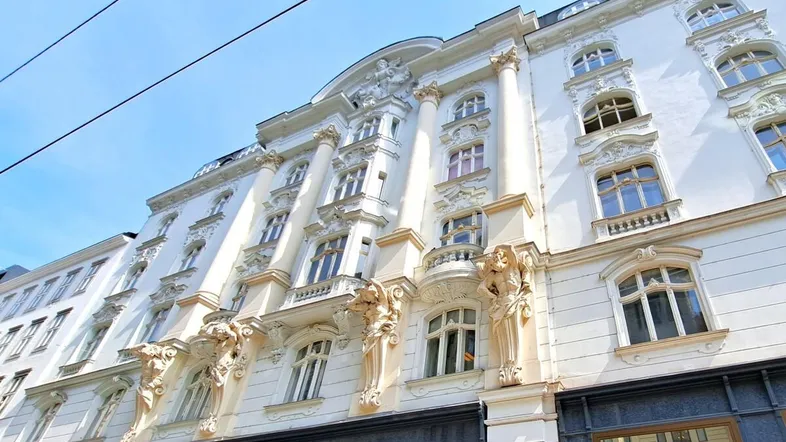 Prächtige historische Fassade eines Gebäudes mit aufwendigen Verzierungen und großen Fenstern.