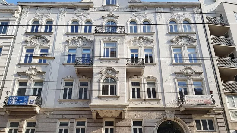 Historisches Gebäude mit reich verzierten Stuckfassaden, kleinen Balkonen und klassischen Fenstern.
