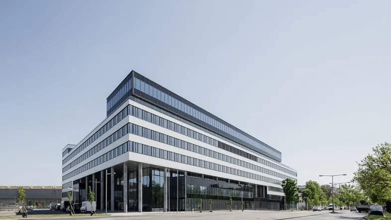 Modernes Bürogebäude mit markanter Architektur und großen Glasflächen an einer Straße gelegen.