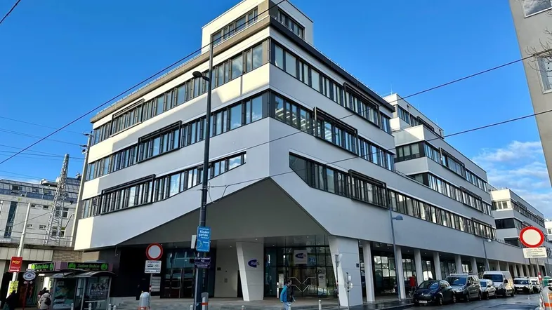 Modernes Bürogebäude mit markanter Architektur und großen Fenstern an einer belebten Straße.