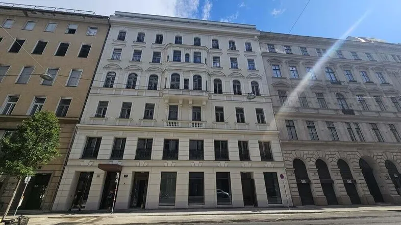 Die Fassade des Gebäudes zeigt klassische Architektur mit mehreren Stockwerken und vielen Fenstern.