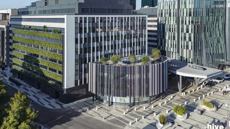 Moderne Bürogebäude mit vertikalen Gärten und einer markanten runden Fassade in einer städtischen Umgebung.