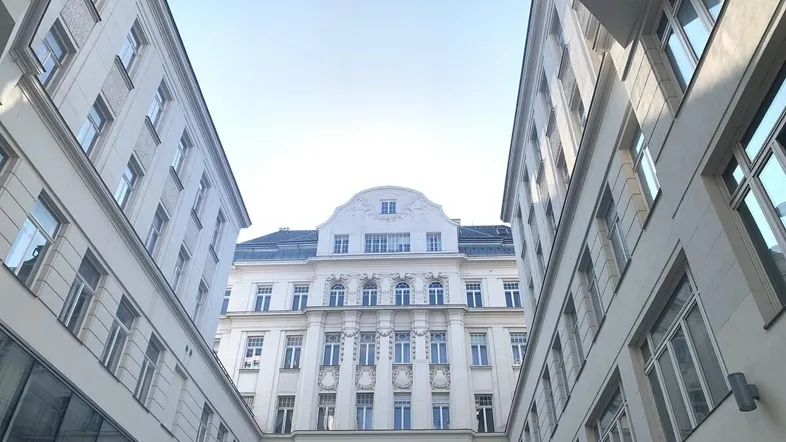 Blick in den Innenhof eines klassischen Gebäudes mit heller Fassade und vielen Fenstern.