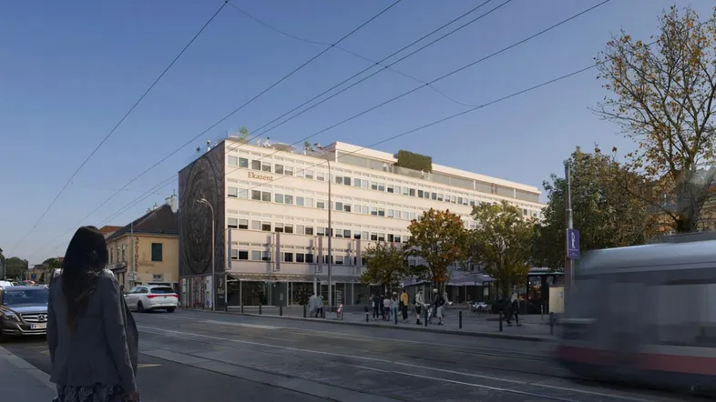 Gebäudeansicht von der Straße mit vorbeifahrender Straßenbahn und städtischer Umgebung an einem sonnigen Tag.