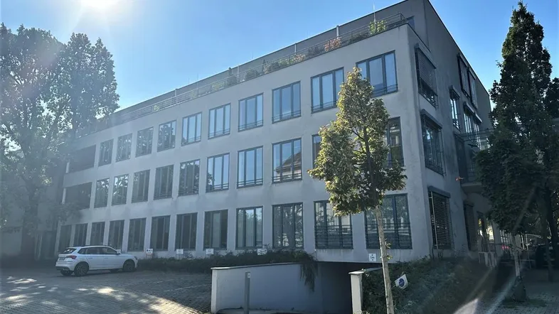 Modernes Bürogebäude mit mehreren Etagen, großen Fenstern und einem sonnigen Eingangsbereich.