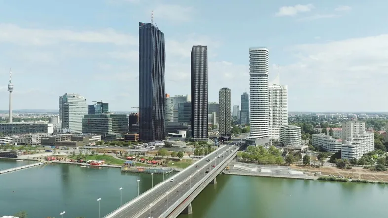 Panoramablick auf die moderne Stadtlandschaft mit Hochhäusern, Fluss und Brücke unter blauem Himmel.