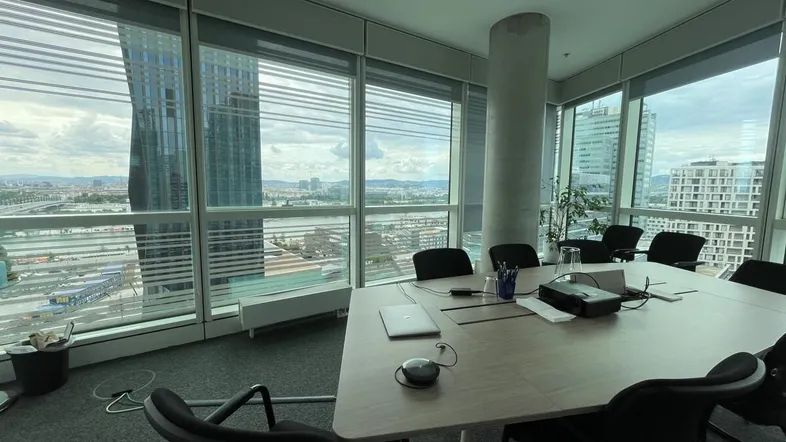 Moderner Konferenzraum mit großen Fenstern, die einen weiten Blick auf die Stadt und die umliegenden Gebäude bieten.