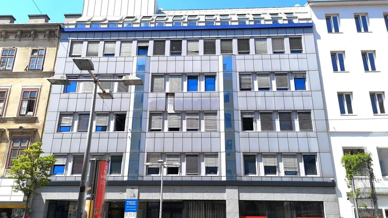 Modernes Bürogebäude mit blauen Akzenten und vielen Fenstern in städtischer Umgebung.