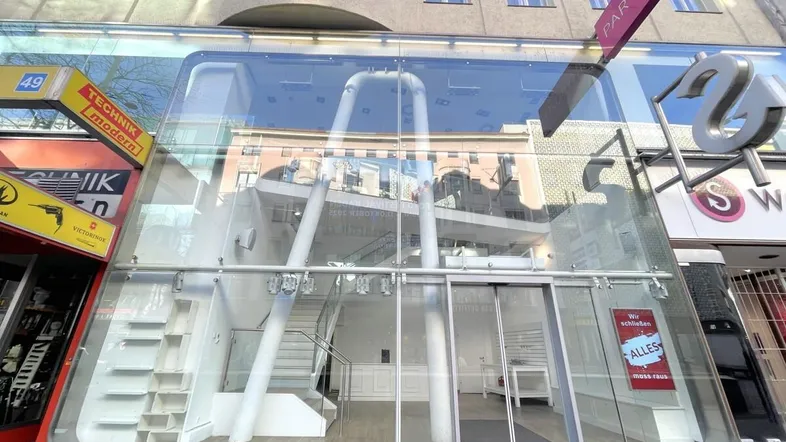 Moderne Geschäftsfassade mit großer Glasfront und Eingangsbereich in einer belebten Einkaufsstraße.