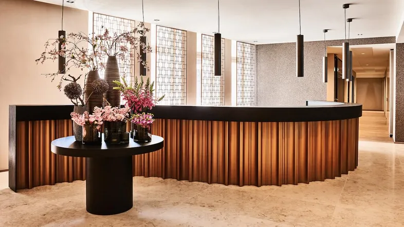 Moderner Empfangsbereich mit eleganter Holztheke, stilvollen Blumenarrangements und indirekter Beleuchtung.