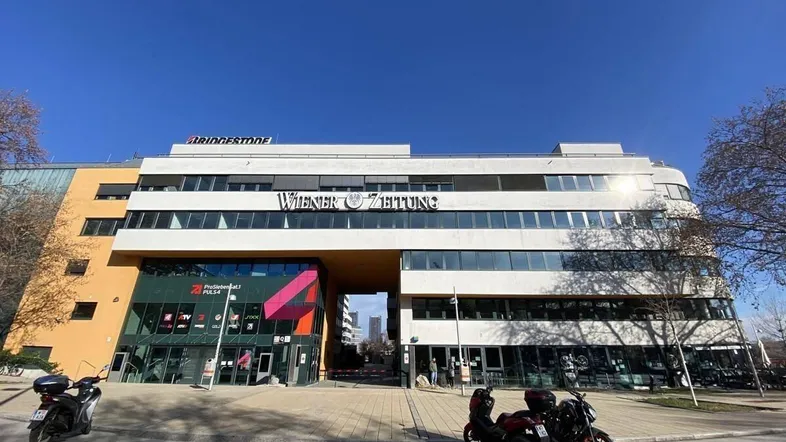 Modernes Bürogebäude mit markanter Architektur und einem Durchgang, der zur Straße führt.