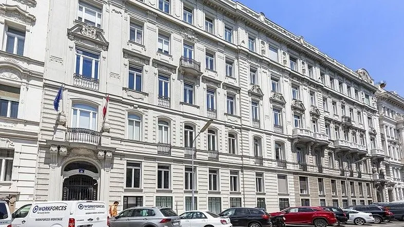 Historisches Gebäude mit klassischer Architektur und vielen Fenstern an einer belebten Straße.