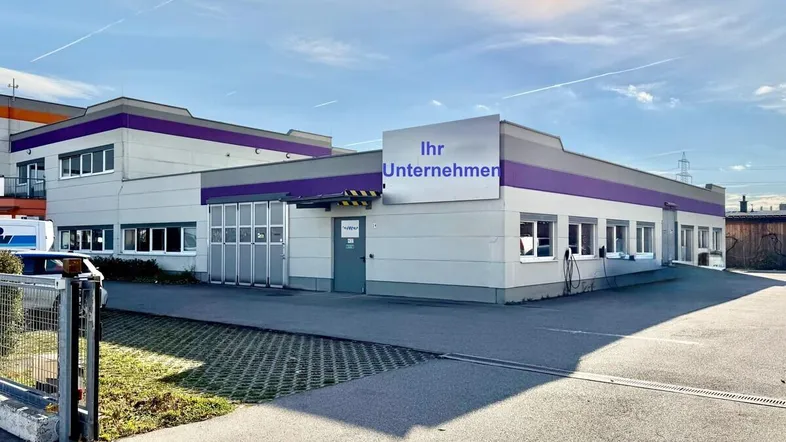 Modernes Geschäftsgebäude mit lila Akzenten und einem großen Parkplatz davor unter blauem Himmel.