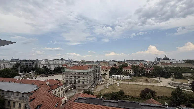 Panoramablick über die Stadt mit historischen Gebäuden, einem Park und bewölktem Himmel.