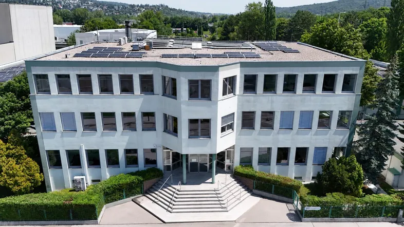 Modernes Bürogebäude mit mehreren Etagen, großen Fenstern und Photovoltaikanlage auf dem Dach.
