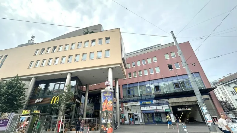Mehrstöckiges Gebäude mit Geschäften im Erdgeschoss und Büros darüber, an einer belebten Straße gelegen.