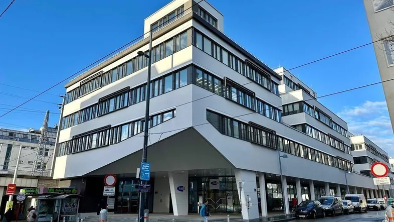 Modernes Bürogebäude mit markanter Architektur und Geschäften im Erdgeschoss an einer belebten Straße.