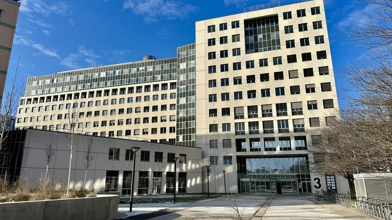 Modernes Bürogebäude mit mehreren Etagen und einer klaren, funktionalen Architektur unter blauem Himmel.