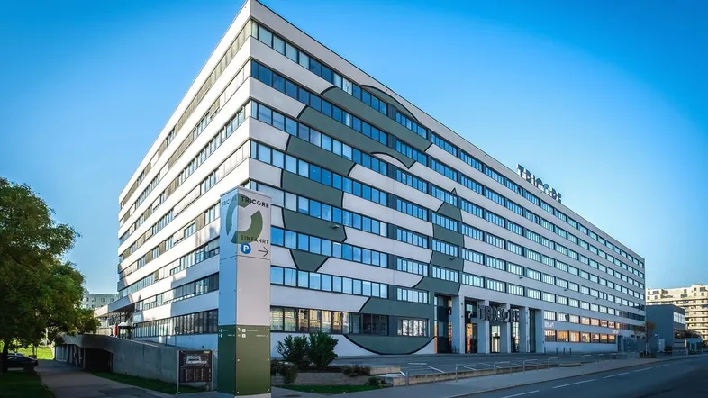 Modernes Bürogebäude mit markanter Fassadengestaltung und vielen Fenstern unter blauem Himmel.