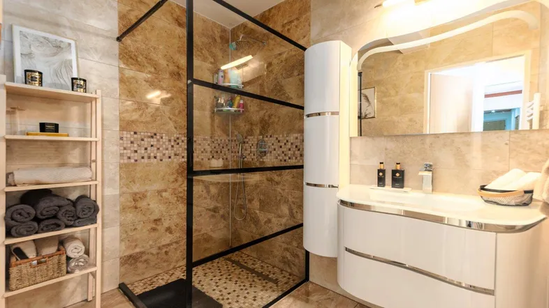 Modernes Badezimmer mit begehbarer Dusche, elegantem Waschtisch und hellen Fliesen.