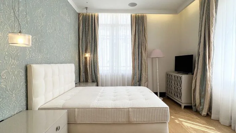 Helles Schlafzimmer mit Holzboden, großem Bett, dekorativer Tapete und hohen Decken.