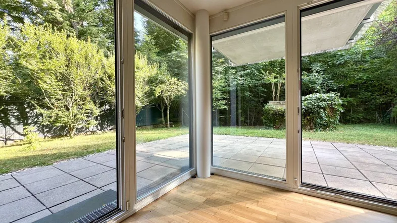 Heller Wohnbereich mit großen Glasfronten und direktem Zugang zur Terrasse und zum Garten.