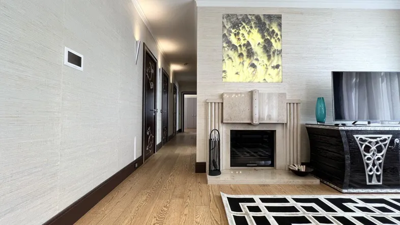 Langer Flur führt zu einem eleganten Wohnzimmer mit Kamin und modernem Teppich.