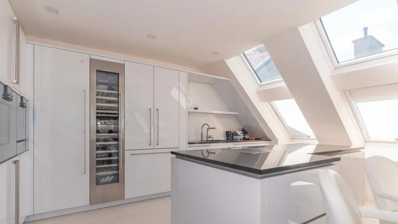 Moderne Küche mit weißen Hochglanzfronten, Dachfenstern und integriertem Weinkühlschrank.