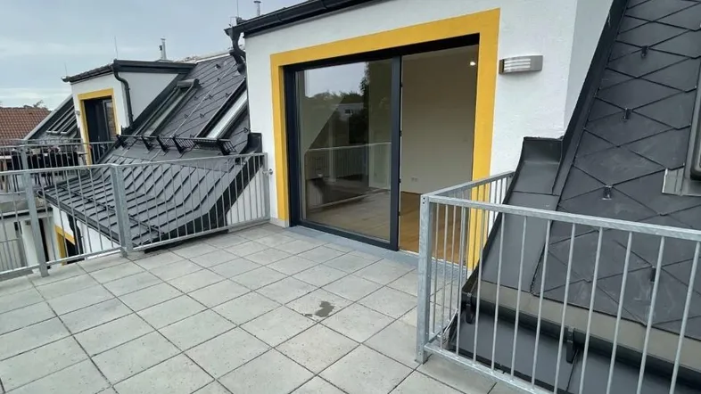 Geräumige Dachterrasse mit modernen Fliesen und Blick auf die Umgebung, zugänglich vom Innenbereich.