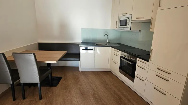 Moderne Einbauküche mit hellen Fronten, integrierten Geräten und gemütlicher Essecke.