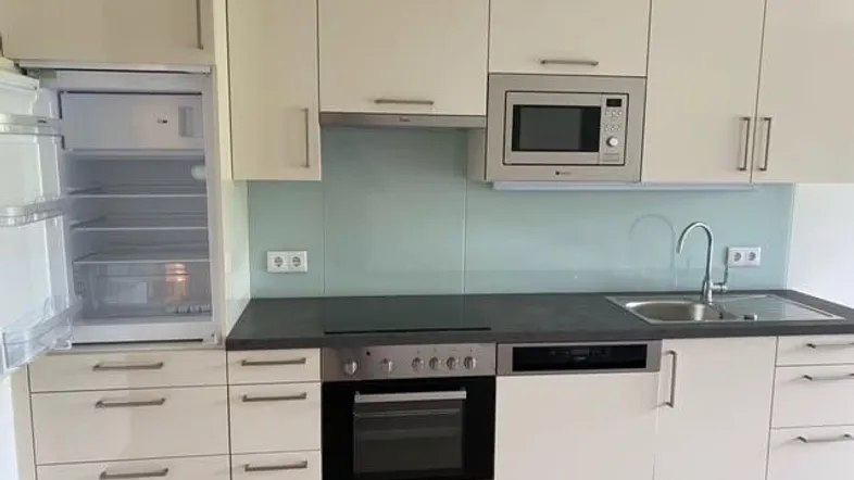 Moderne Einbauküche in Beige mit integrierten Geräten, Spüle und Mikrowelle.