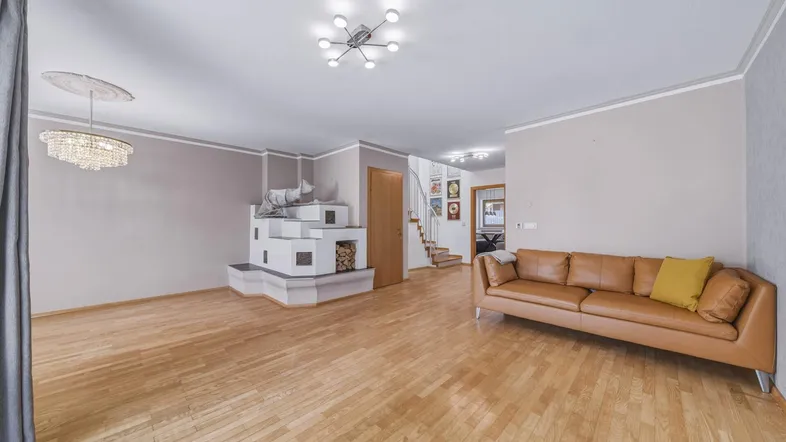 Geräumiges Wohnzimmer mit hellem Parkettboden, modernem Kachelofen und bequemer Ledercouch.