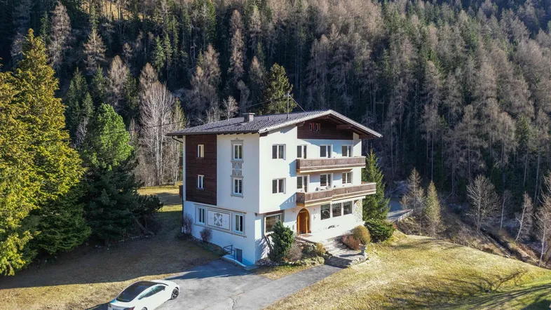 Großzügiges Wohnhaus in alpiner Umgebung mit umliegenden Wäldern und Bergen.