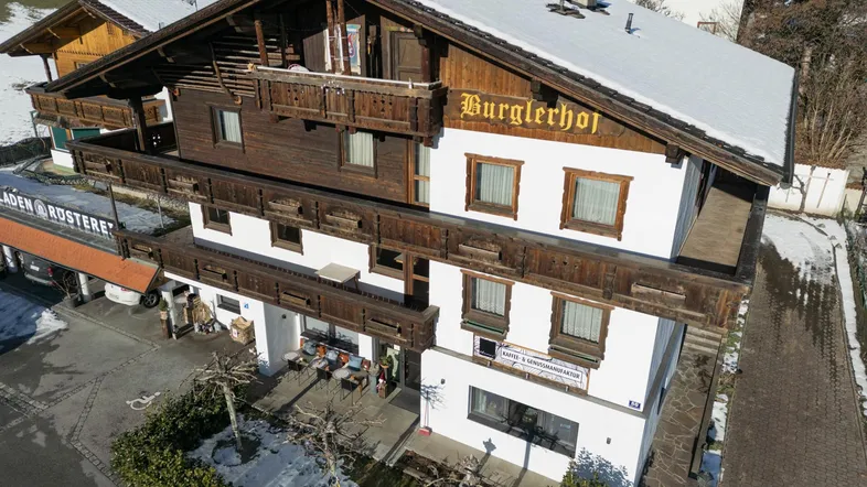 Traditionelles Gebäude im alpinen Stil mit Holzbalkonen und verschneitem Dach in bergiger Umgebung.