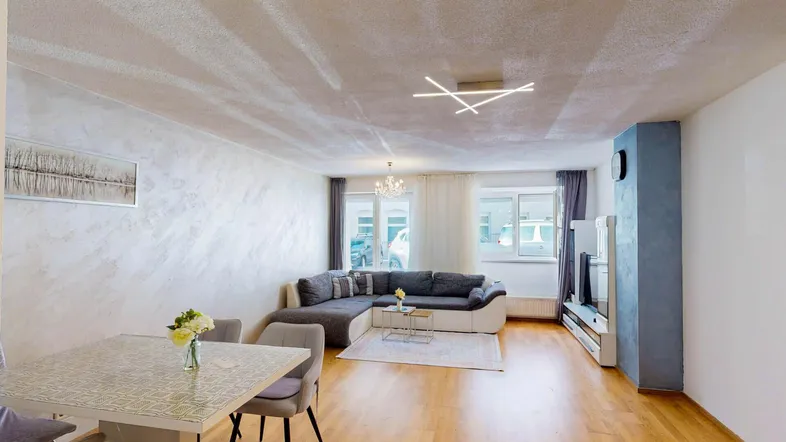 Helles Wohn- und Esszimmer mit Parkettboden, bequemer Eckcouch und modernem Esstisch.