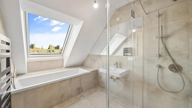 Modernes Badezimmer im Dachgeschoss mit Badewanne, Dusche und großem Dachfenster für viel Tageslicht.