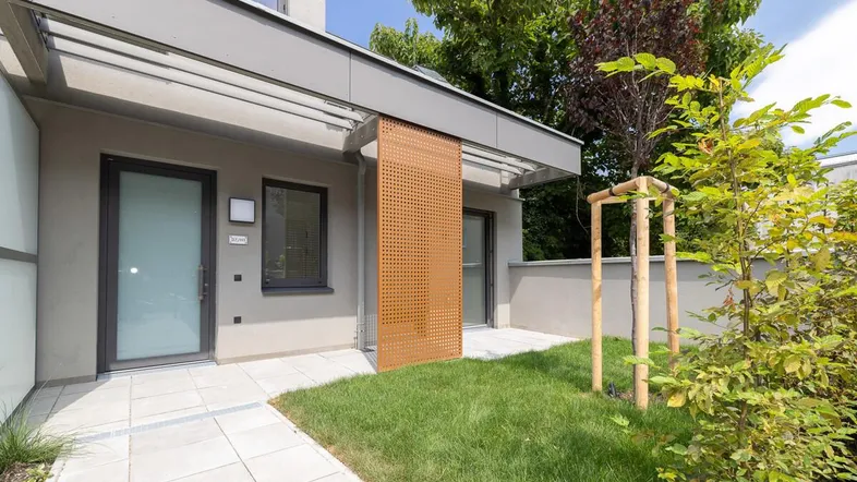 Moderne Erdgeschosswohnung mit kleiner Terrasse und eigenem Gartenanteil, umgeben von Grün.