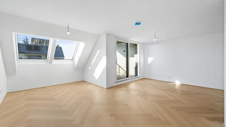 Helles Zimmer mit Dachschrägen, Fischgrätparkett und Zugang zu einem Balkon oder einer Terrasse.