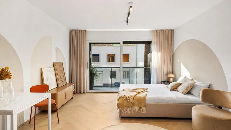 Helles Schlafzimmer mit modernem Design, Holzboden und Zugang zu einem Balkon.