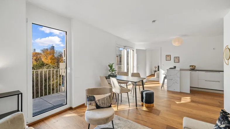 Heller, offener Wohn- und Essbereich mit integrierter Küche und Zugang zum Balkon.