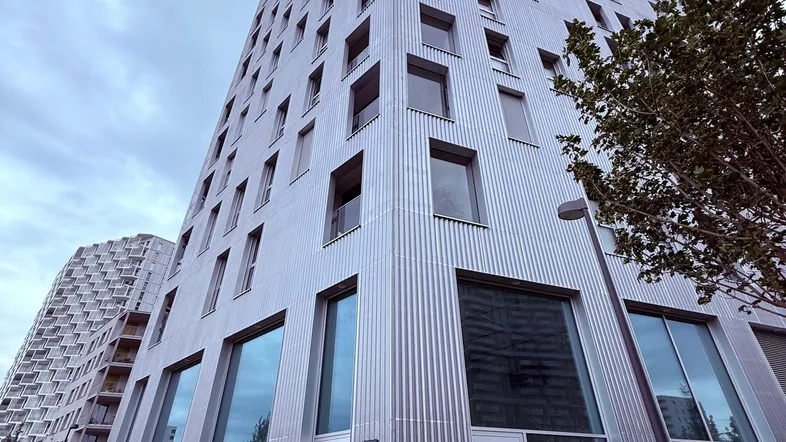 Modernes Hochhaus mit markanter Fassade und vielen Fenstern unter bewölktem Himmel.