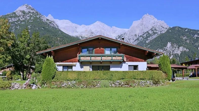 Traditionelles Haus im Alpenstil mit Holzbalkon und beeindruckendem Bergblick.