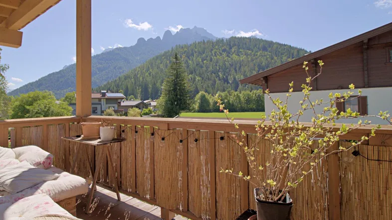 Sonniger Balkon mit Holzboden und Bambusverkleidung, bietet einen atemberaubenden Blick auf die umliegenden Berge und Wälder.
