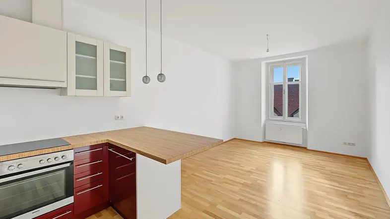 Helle Wohnküche mit Holzboden, moderner Küchenzeile und Blick aus dem Fenster.