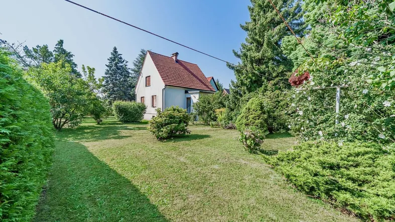 Großzügiger Gartenbereich mit gepflegtem Rasen und Blick auf das Einfamilienhaus unter blauem Himmel.