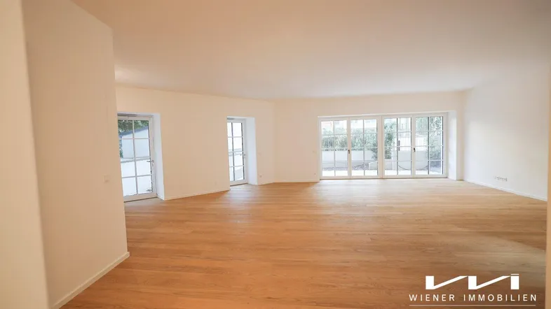 Geräumiges, helles Wohnzimmer mit neuem Parkettboden und Zugang zu einer Terrasse.