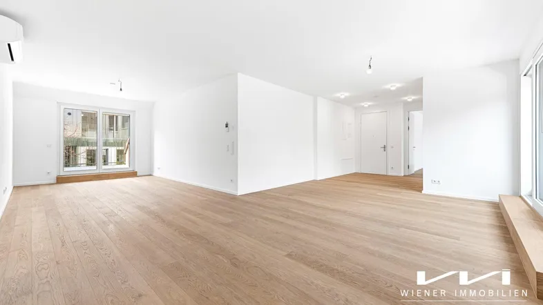 Helles, geräumiges Wohnzimmer mit neuem Parkettboden und Zugang zu einem Balkon.