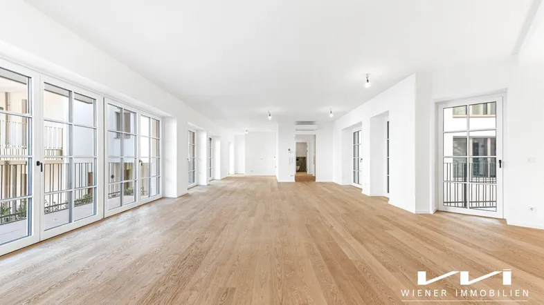 Helles, geräumiges Wohnzimmer mit Parkettboden und vielen Fenstern zu französischen Balkonen.