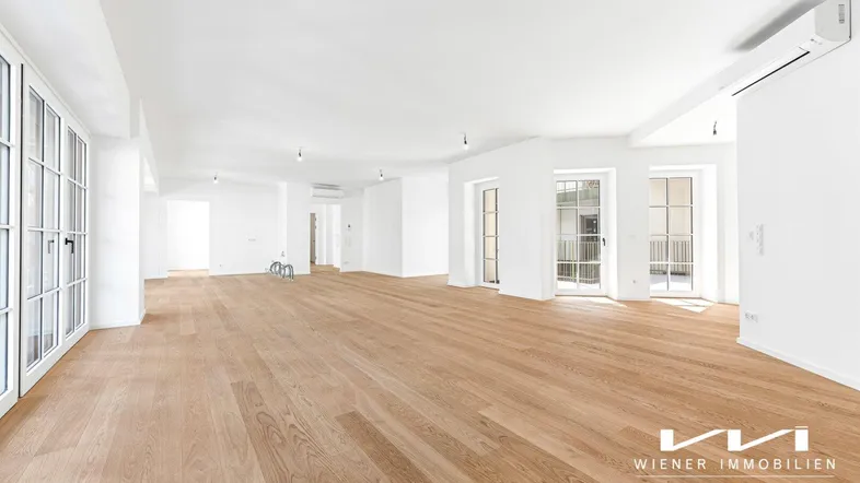 Geräumiger, heller Wohnbereich mit neuem Holzparkettboden und Zugang zu mehreren Balkonen.