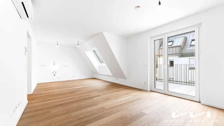 Heller Wohnbereich mit Eichenparkett, Dachschräge, Dachfenster und Zugang zum Balkon.